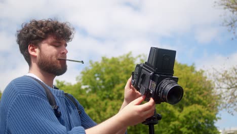 photographer using retro photo camera and taking pictures outdoors - close up