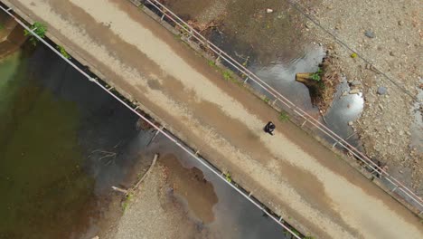 A-girl-walks-over-a-bridge-with-a-river-flowing-beneath-her-at-the-northern-village-of-Grande-Riviere,-Trinidad-and-Tobago