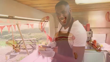 Animation-of-hot-dogs-over-happy-african-american-man-preparing-fast-food