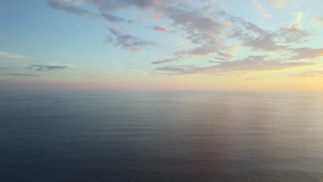 high altitude drone pan over tranquil ocean waters during a majestic sunset