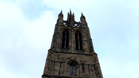 pan video of an old english church tower in a cloudy day