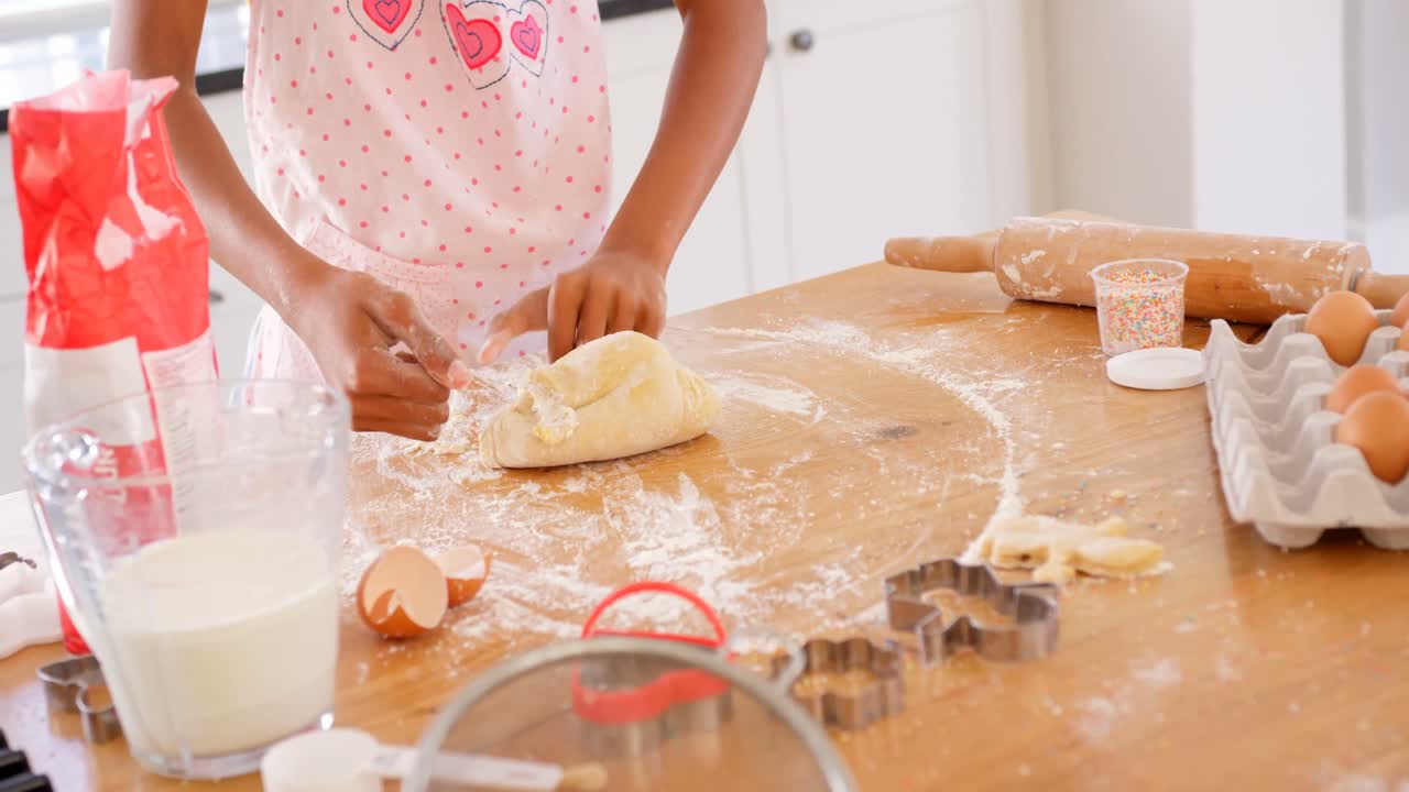 Mid section of black girl kneading dough on worktop in kitchen of comfortable home 4k