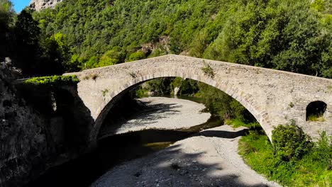 aéreo: hombre caminando sobre un antiguo puente de piedra sobre el río