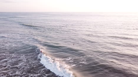 persona activa surfeando sobre las grandes olas con un cielo brillante en el fondo en la playa de olón en ecuador