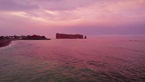 Vista-De-Drones-Sobre-El-Río-San-Lorenzo-Que-Revela-La-Roca-Percé-Durante-Una-Puesta-De-Sol-Nublada