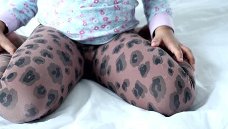 toddler girl sitting on a bed wearing leopard print leggings