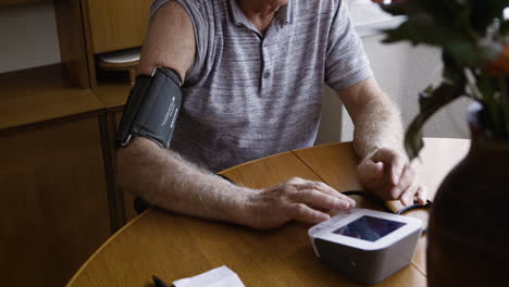 senior man checking blood pressure at home