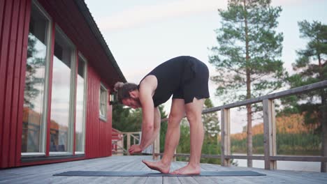 man doing forward bend stretching on yoga mat