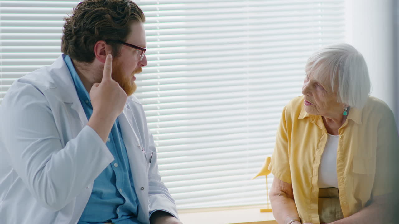 Old Woman Having Talk with Male Doctor in Clinic