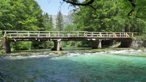 an old wooden bridge in slovenia crossing the river with clear water and beautiful colors