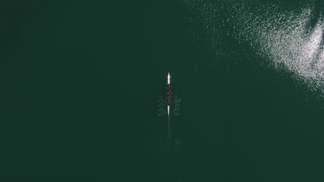 vista aérea aérea del equipo de remo en bote remando juntos en aguas abiertas verdes