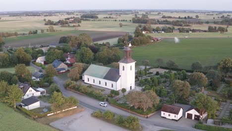 Tiro-De-Drone-De-La-Iglesia-Con-Campos-De-Cultivo-En-El-Fondo-En-Skane,-Sur-De-Suecia