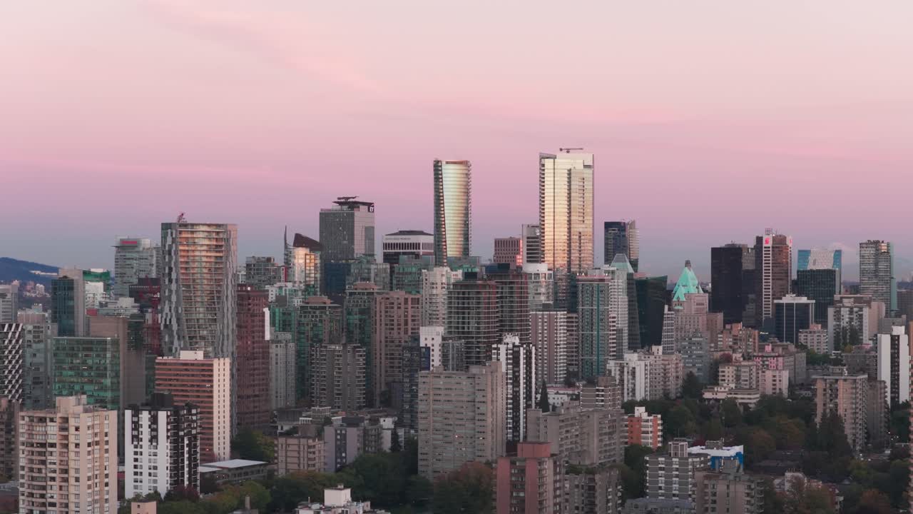 Telephoto wide panning aerial shot of the glowing skyline of downtown Vancouver during sunset in British Columbia, Canada. 4K