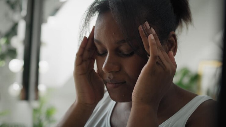 Nahaufnahme einer afroamerikanischen Frau mit starken Kopfschmerzen, die im Badezimmer steht.