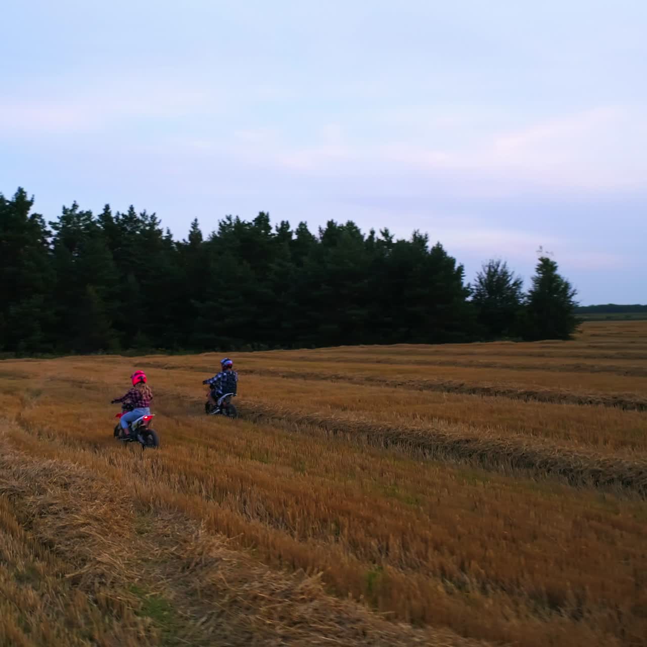 Uomo e donna che guidano motociclette leggere in campagna. Giovane coppia che si diverte guidando i veicoli. Vista dall'alto con discesa graduale