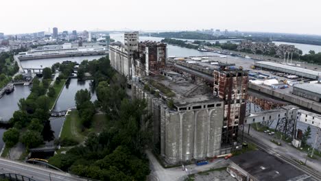 aerial view of rusted industrial silos with a modern city skyline backdrop. a stunning contrast of urban decay and sleek architecture. montreal's old port docks.
