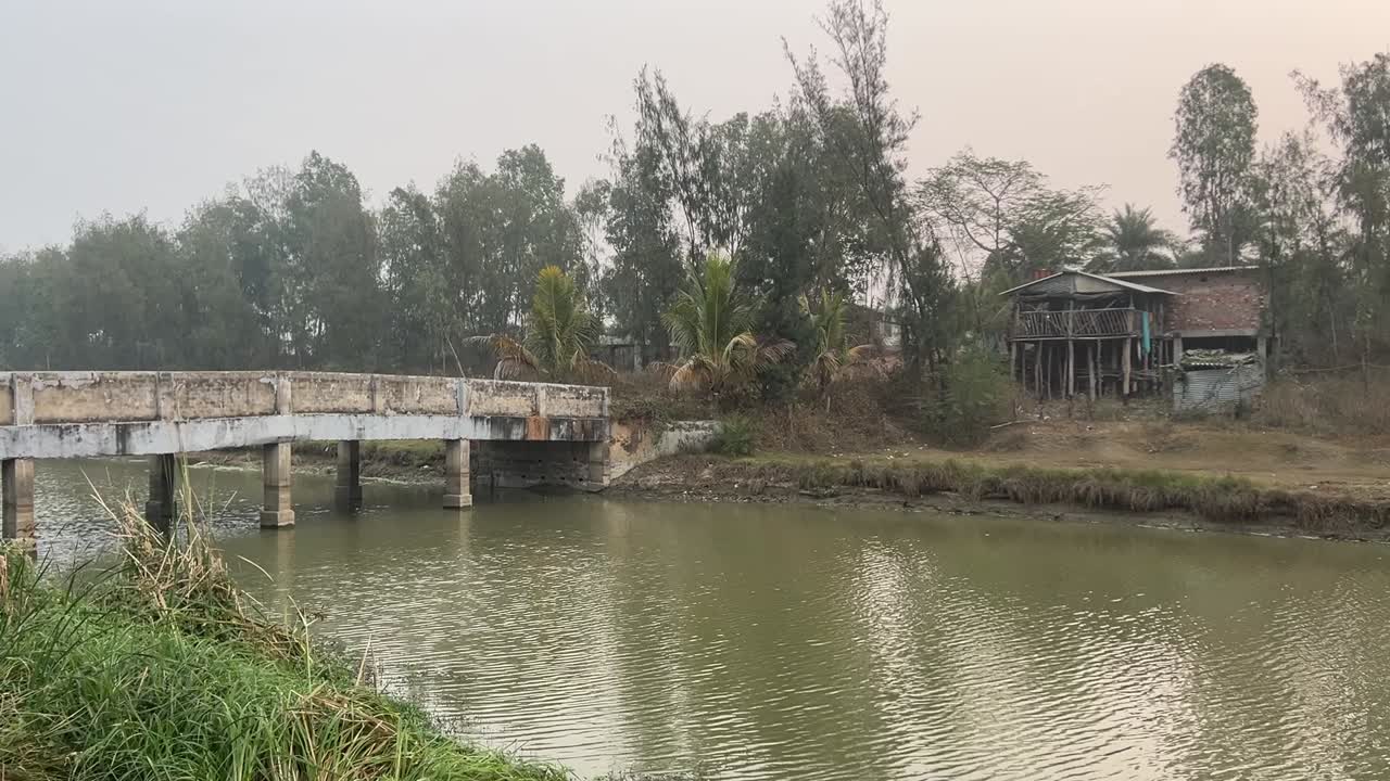 un viejo puente de pie firme sobre un lago al lado de una casa de madera en kolkata, india