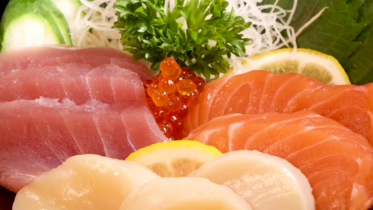 Bacchette di legno sollevano salmone fresco da un vivace set di sashimi con tonno e capesante