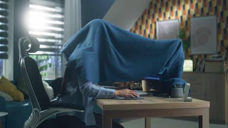 woman hiding behind a blanket while working from home