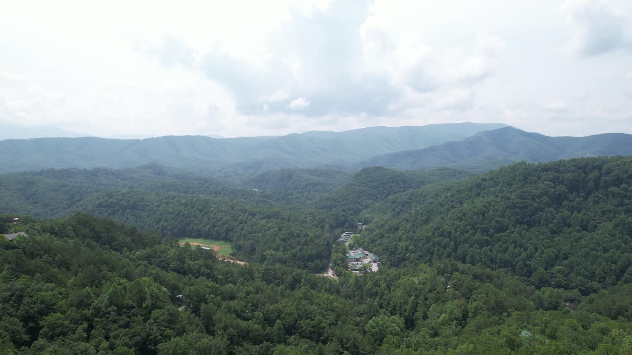 Smooth zoom in showcasing forested mountain range with a small village in the distance.