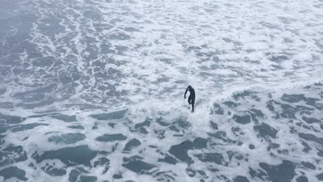 Surfista-Montando-Una-Ola-De-Cal-A-Baja-Velocidad-En-Islandia,-Antena