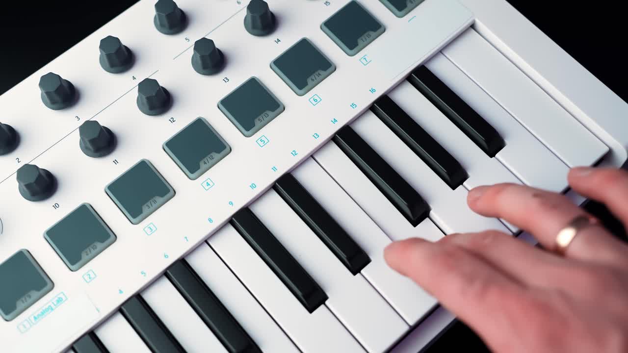 Primo piano di una mano che suona note su una tastiera MIDI compatta con pad e manopole, che illustra la composizione in home studio, il beatmaking e il flusso di lavoro della musica digitale.