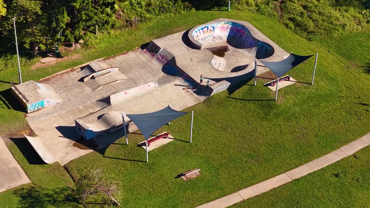 High angle aerial drone shot of an empty outdoor concrete skate park with graffiti art