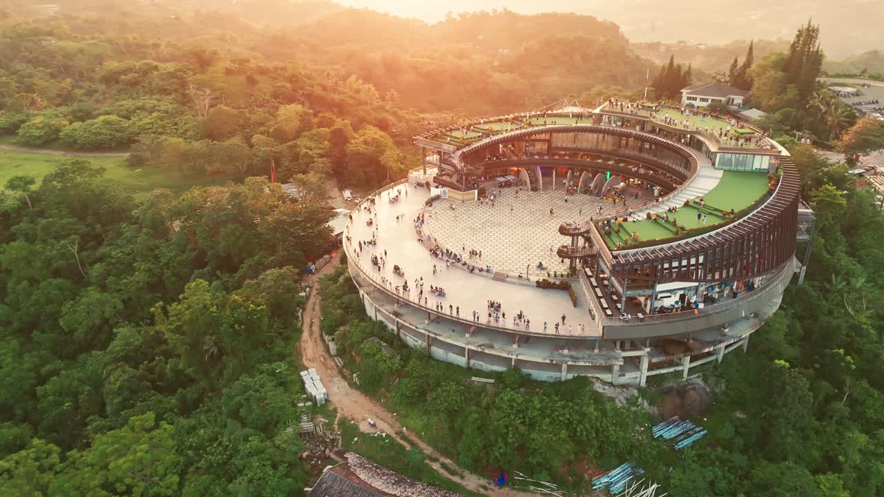 Golden hour aerial drone shot of Cebu’s Tops Lookout, tourists enjoying the circular landmark surrounded by lush green mountains. Ideal for travel and tourism projects