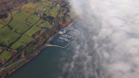 carlingford marina with surrounding green fields and dense clouds rolling in , aerial view