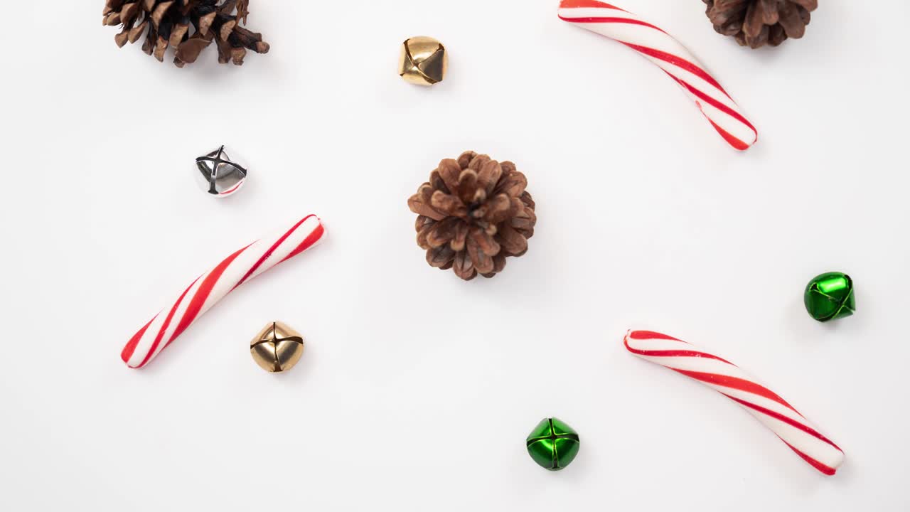 hermoso bucle de fondo de vacaciones de conos de pino, palos de caña de caramelo, y campanas de jingle verdes, doradas y plateadas rápidamente añadiendo y quitando una a la vez.