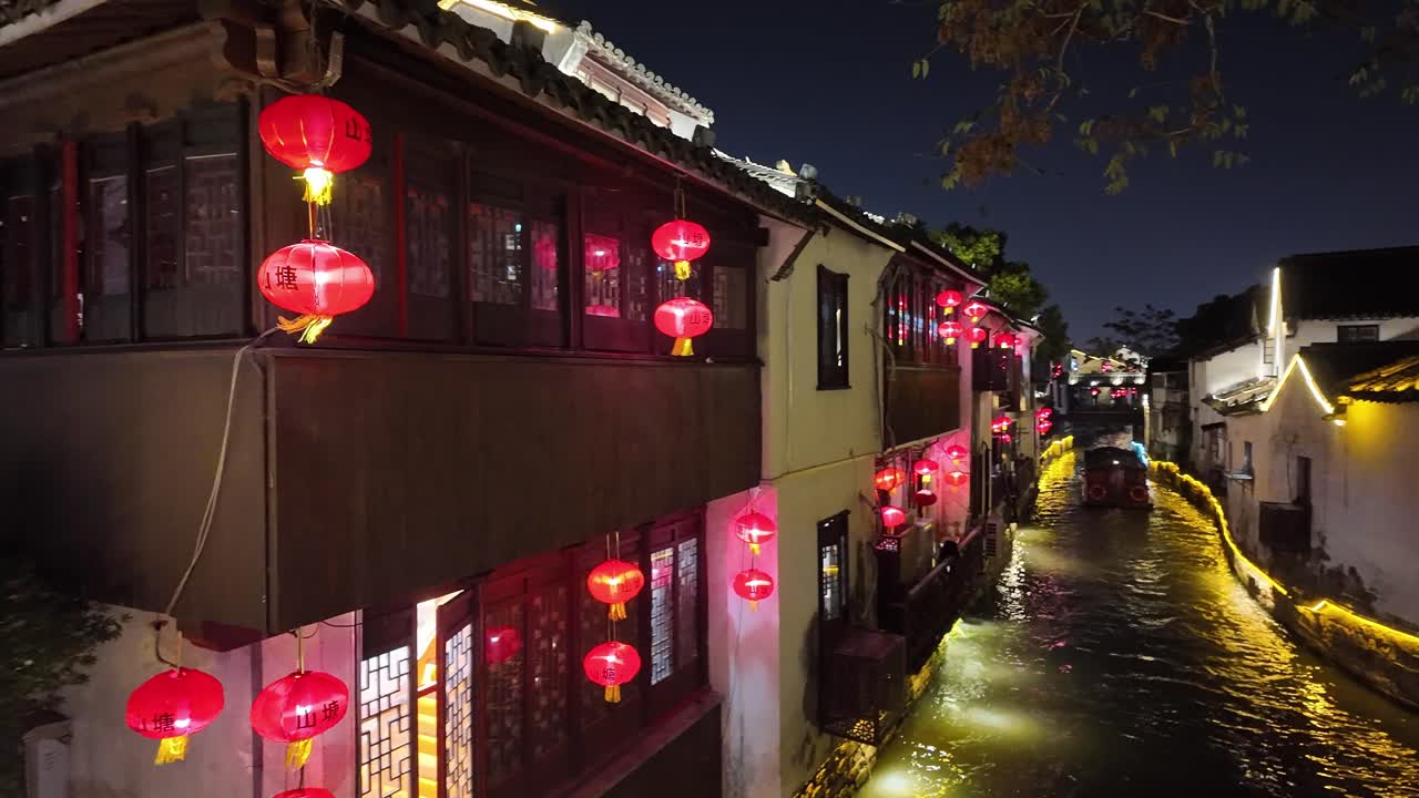 Charming night scene of Hangzhou canal with glowing red lanterns and traditional Chinese houses reflecting beautifully on the water