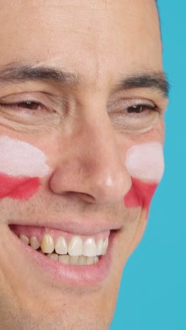 happy man with polish flag painted on face looking away
