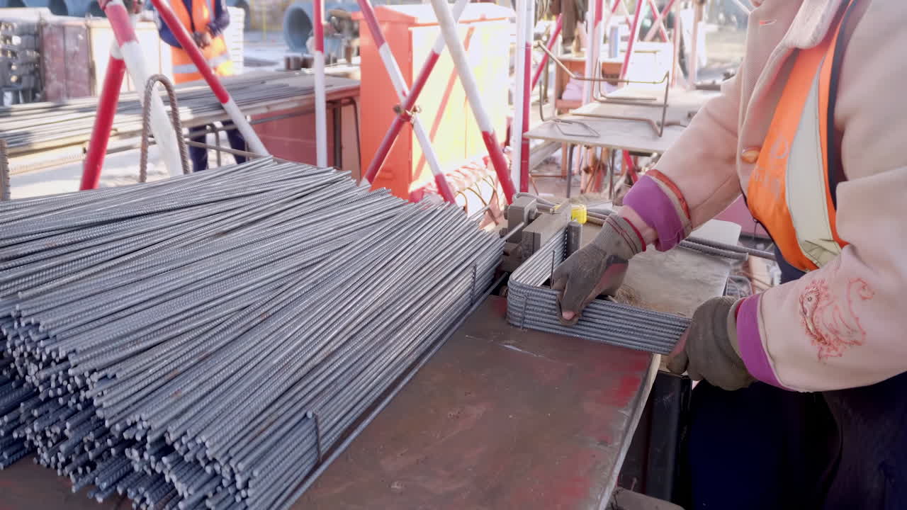 Construction workers in uniforms, hard hats working on new building site. Laborer fabricating steel reinforcement bars at a modern construction site, showcasing dedication and effort