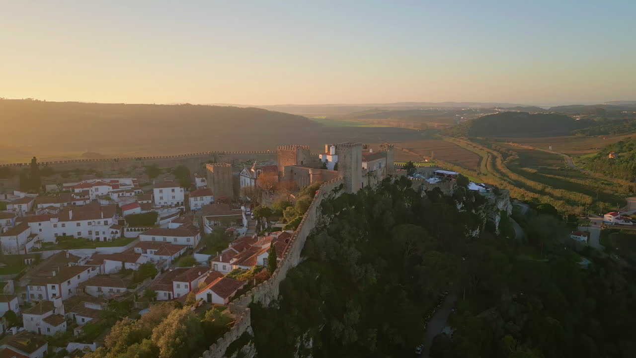 Stone castle overlooking village at picturesque sunset light. Fortress walls