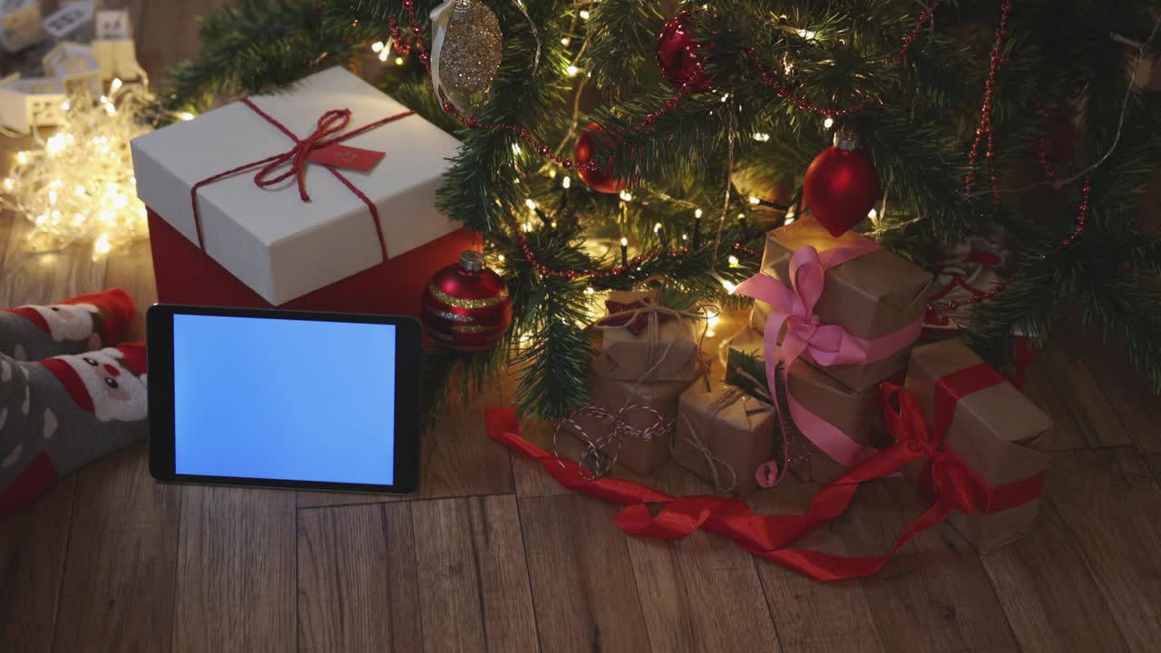 navidad cajas de regalos de artesanía rojas y tableta pantalla de maqueta azul bajo el abeto