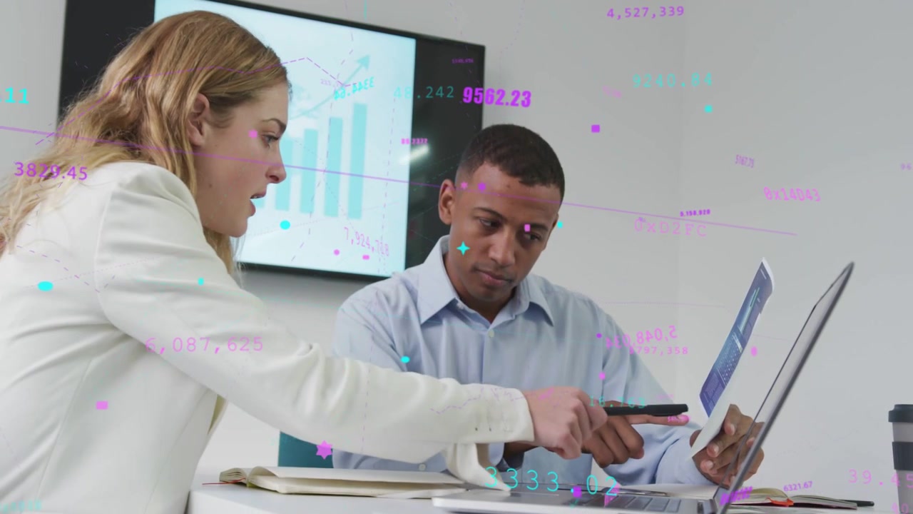 Man holding tablet pointing at laptop, woman pointing, floating data helping review sales chart