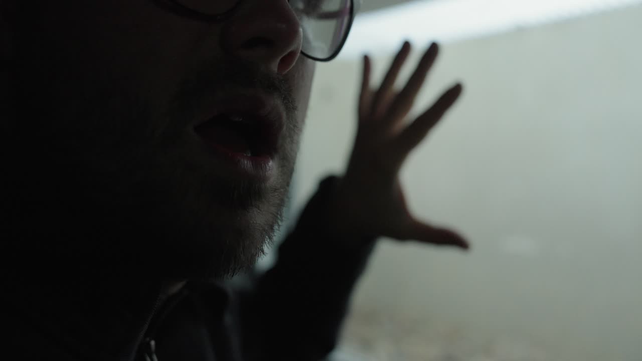 Moody close-up of a man near a window breathing heavily, suggesting panic, exhaustion, or emotional stress in a dark cinematic atmosphere. Ideal for anxiety, burnout, tension, and mental health storyt