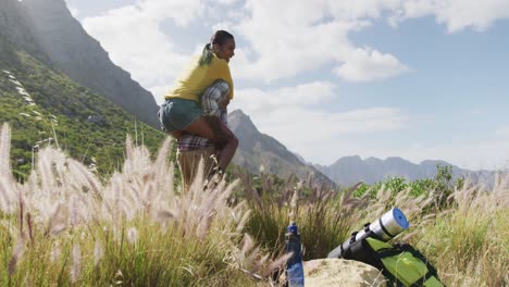 hombre afroamericano dando paseo a hombros a su esposa mientras hace senderismo en las montañas