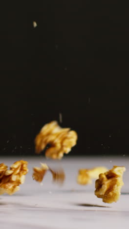 video vertical de primer plano de nueces cayendo sobre la superficie de mármol filmado en cámara lenta