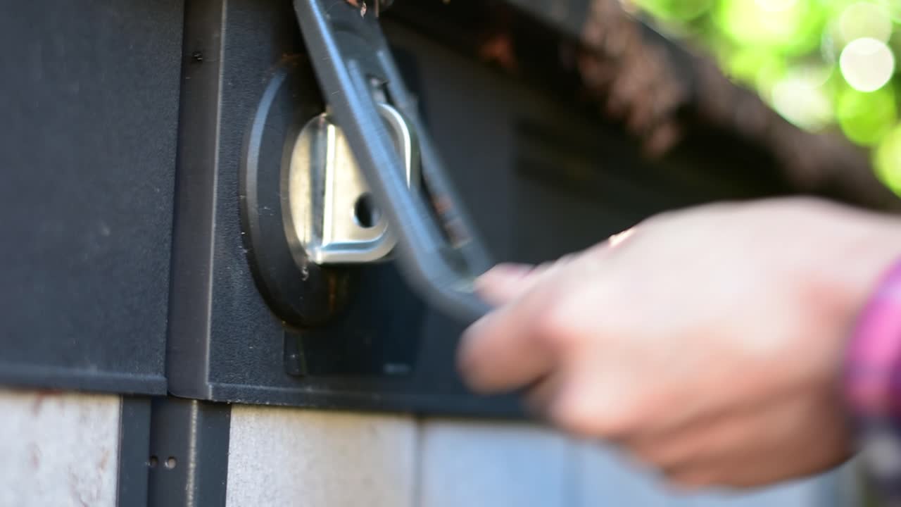 красиво снятый альтернативный угол экстремальный крупный план замка и замка на сарае с руками, протягивающимися, чтобы использовать ключ для разблокировки и удаления замка и разблокировки крышки и двери, с стильным боке