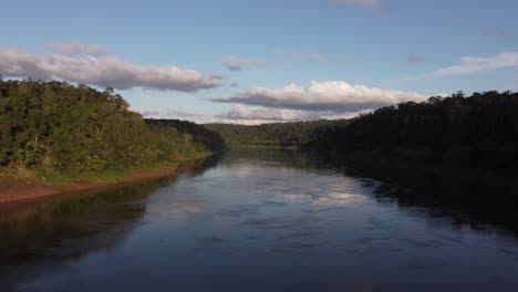 Slow-aerial-forward-flight-over-Iguazu-River-surrounded-by-Amazon-Rainforest-at-sunset---Flight-along-border-of-Brazil-and-Argentina