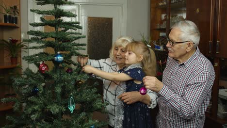 Niña-Con-Familia-De-Abuelos-Mayores-Decorando-árbol-De-Navidad-Artificial,-Vacaciones-De-Año-Nuevo