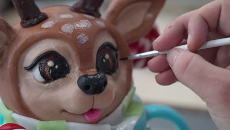close-up of a reindeer sculpture's eye being painted with precision using a fine brush