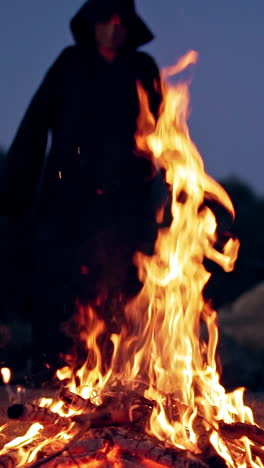man in cassocks by the fire. monk in brown cloaks of the order of st. francis by the fire vertical video