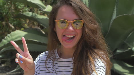 young woman with sunglasses smiling and giving the peace sign