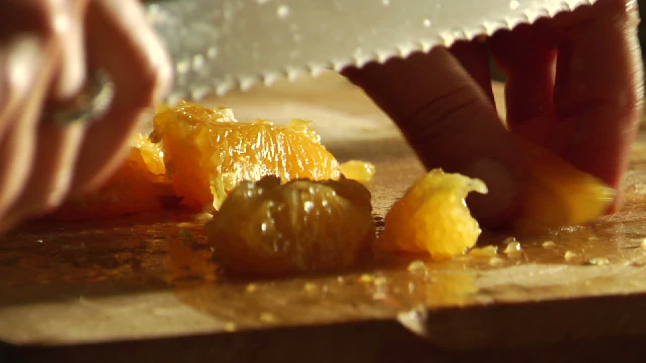 una mujer corta una naranja en una tabla de cortar