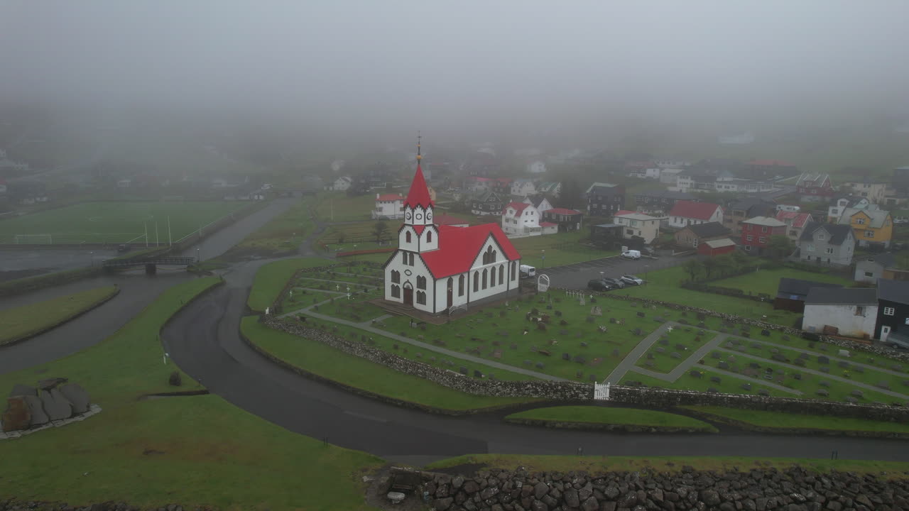 Villaggio di Sandavagur, isola di Vagar: veduta aerea che si estende verso la chiesa nelle Isole Fær Øer