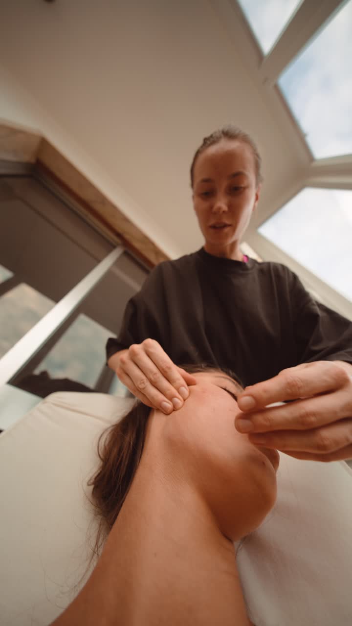Kvinna som får avslappnande ansiktsmassage av professionell kosmetolog