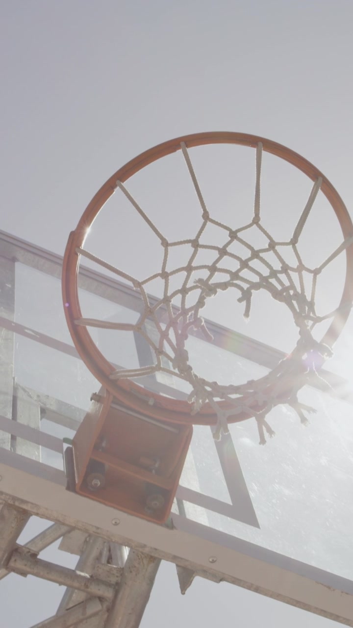 Vista dal basso di un canestro da basket contro un cielo luminoso