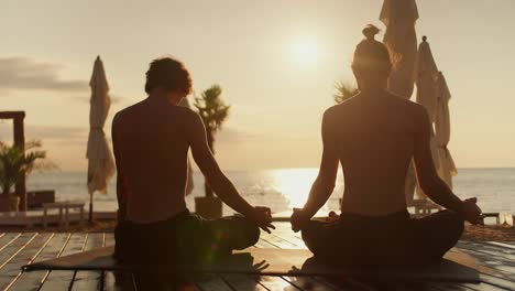 dos tipos se sientan en una alfombra especial y meditan en la playa por la mañana. estilo zen al amanecer